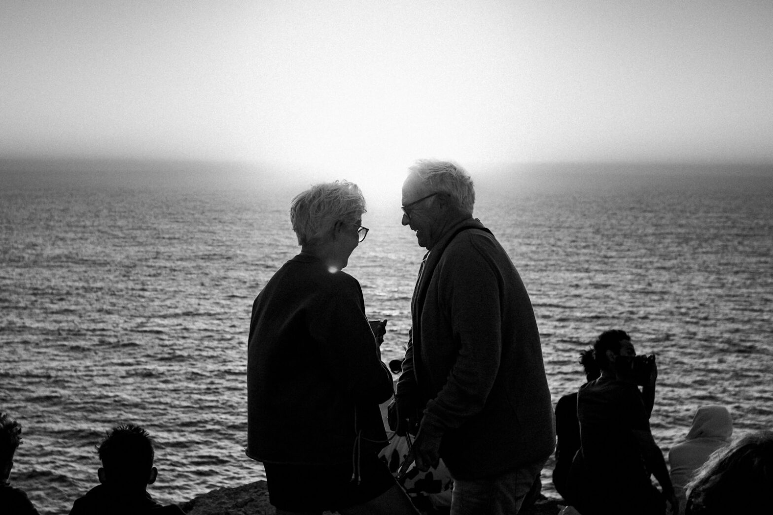 Elderly couple silhouetted against the ocean sunset